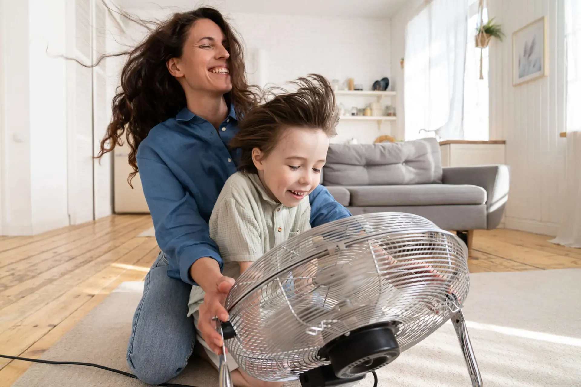 woman and small child holding a fan in front of their faces and enjoying the breeze